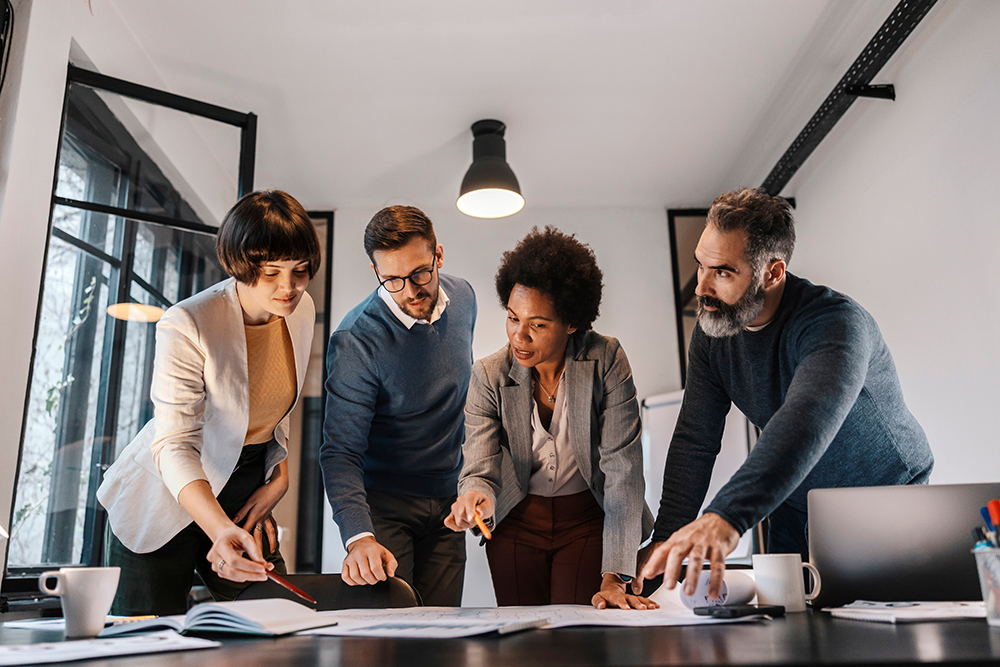 Group of business people pointing at the blueprints