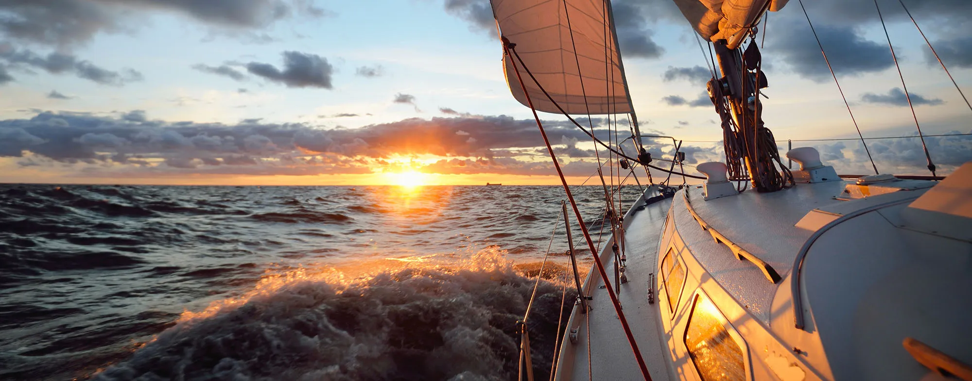 Yacht sailing in an open sea at sunset